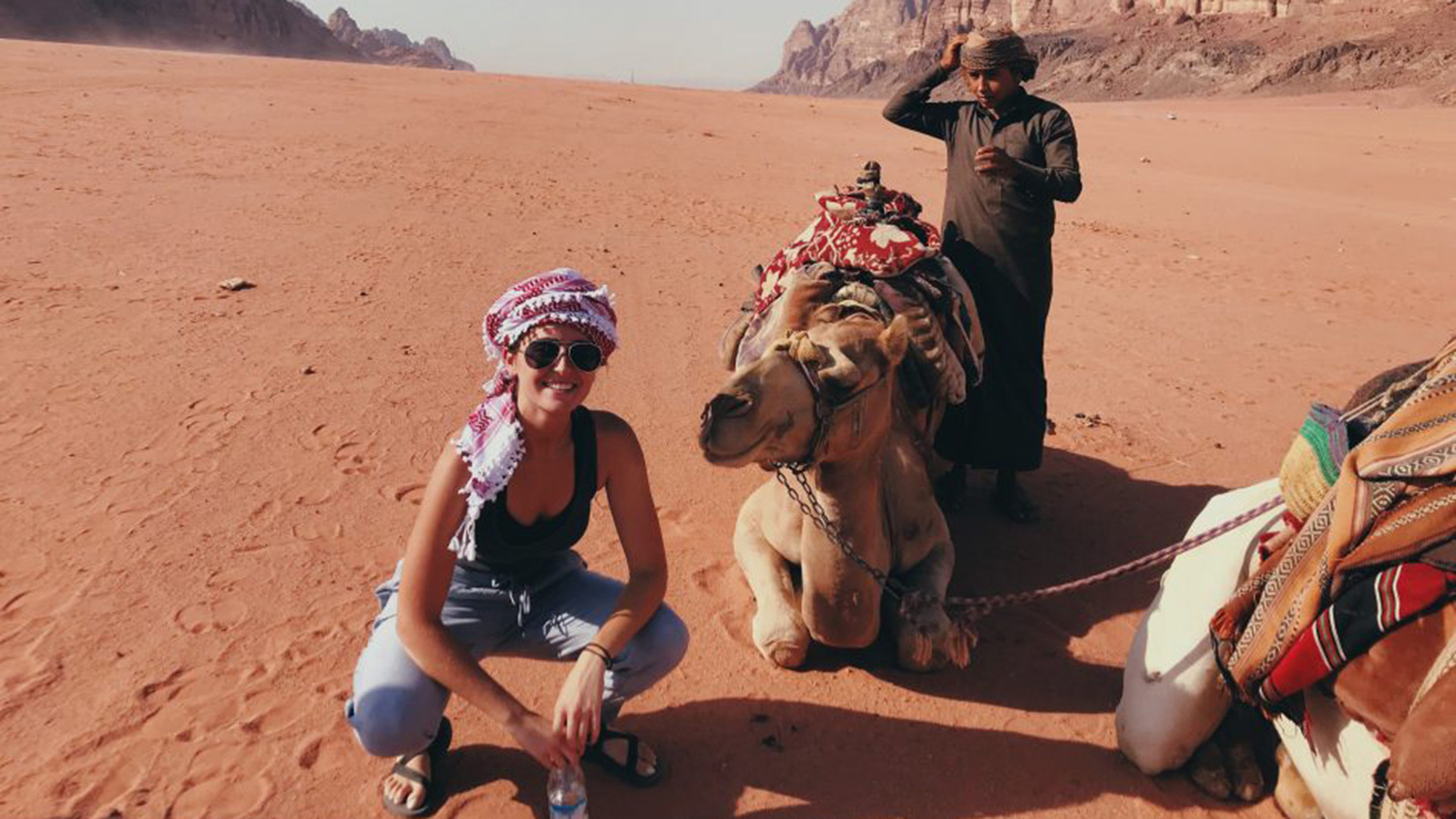 student in front of camel in desert