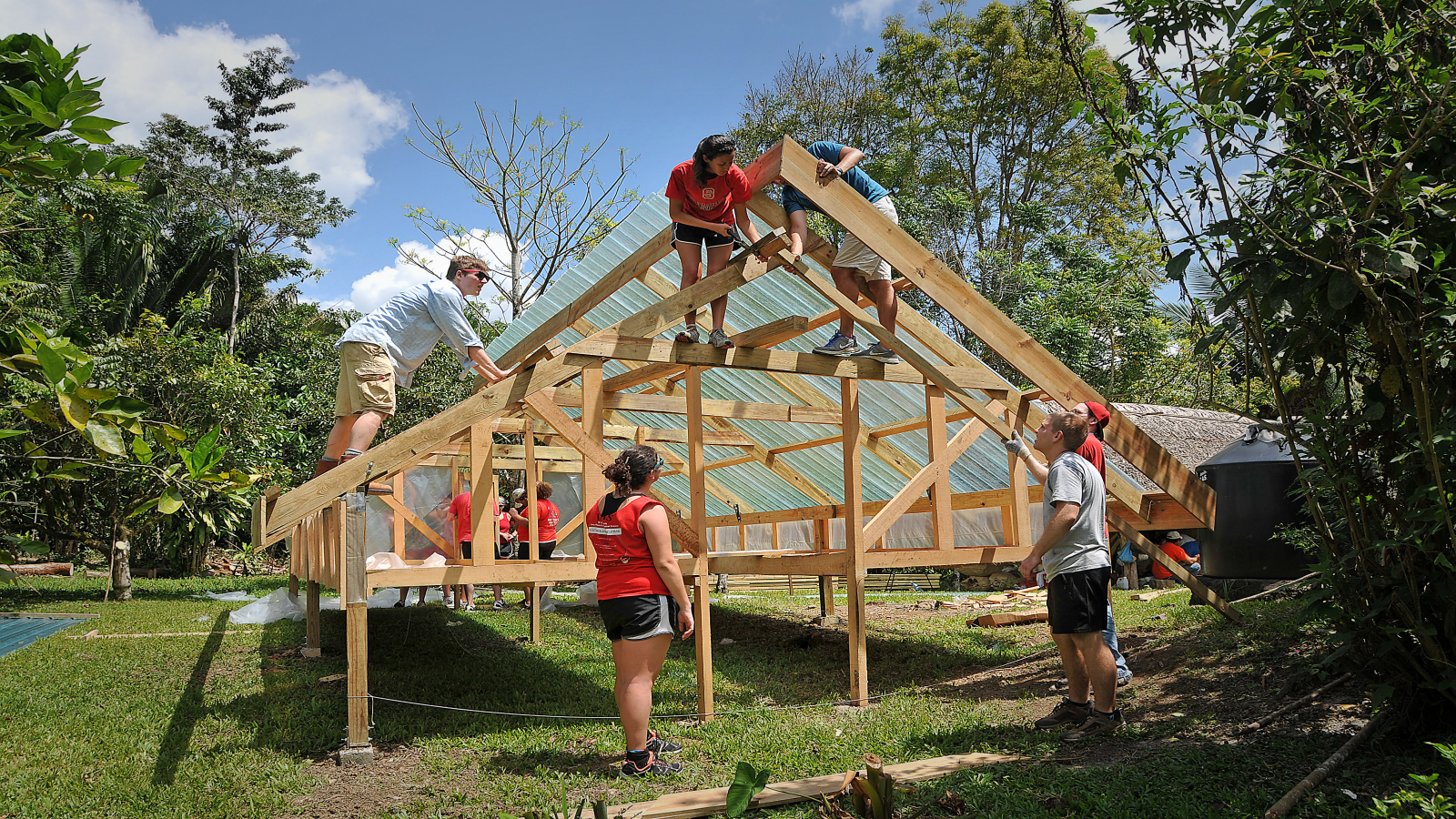 Student volunteers work on building a house frame