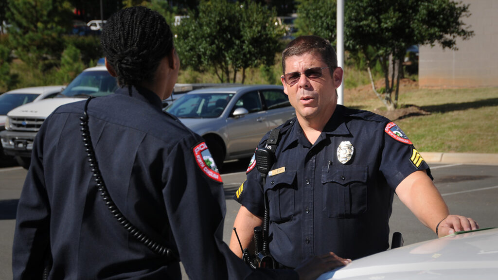 two officers talking while leaning against car