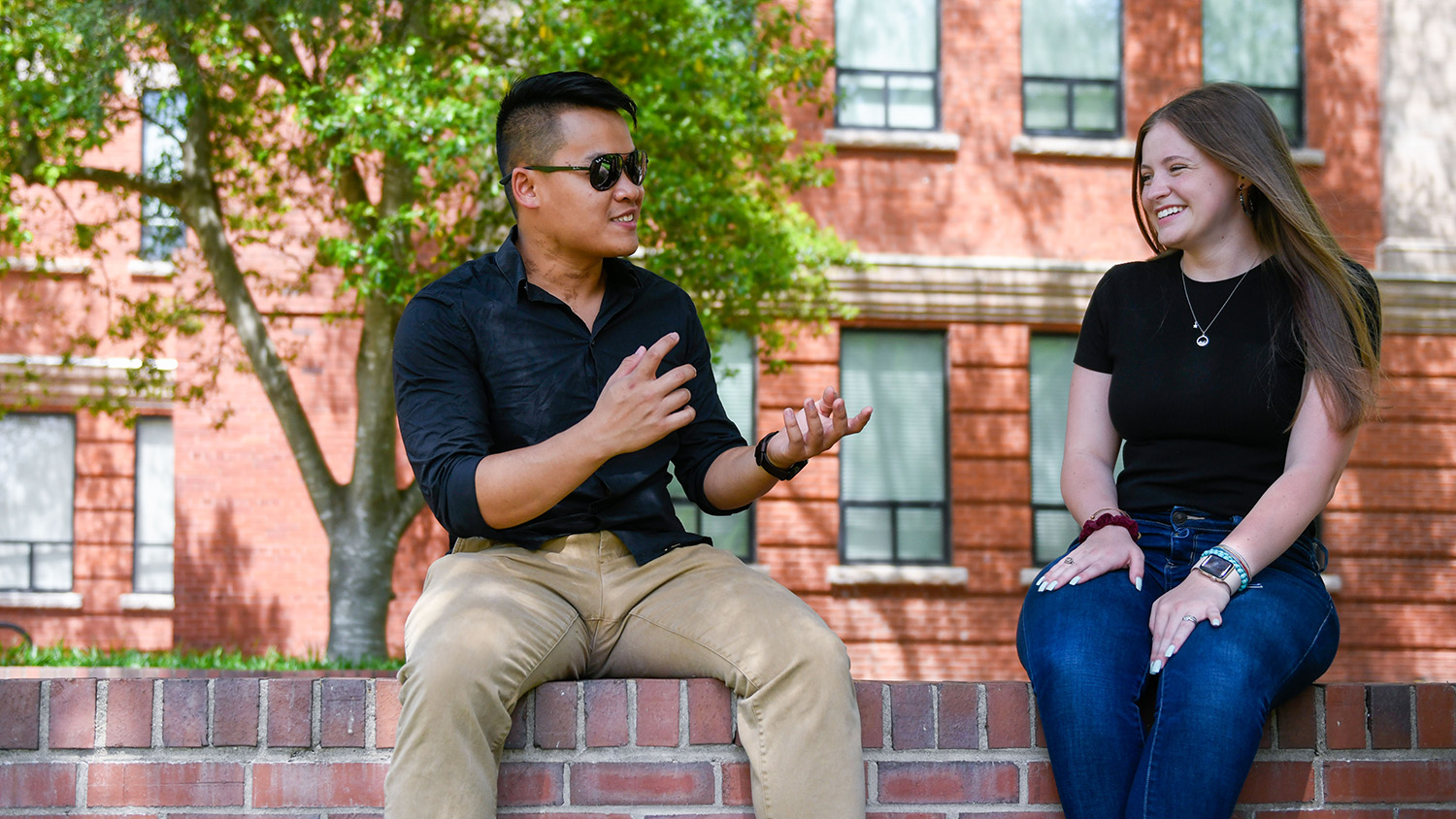students sitting on brick ledge talking