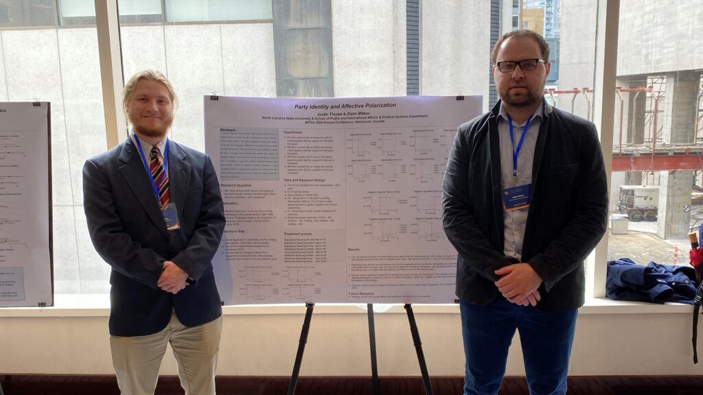 Justin Thorpe and Dr. Zlatin Mitkov stand by Justin's research poster at the Western Political Science Association 2024 Annual Meeting in Vancouver, British Columbia.